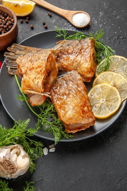 Bottom view fish fry black pepper in bowl mint lemon slices wooden spoon on black table