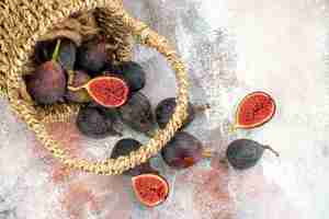 Free photo bottom view fresh figs scattered from basket on nude background