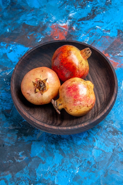 Free photo bottom view fresh pomegranates in wooden bowl on blue background