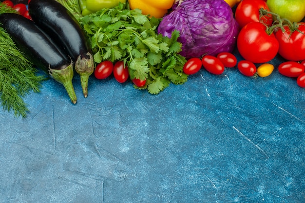 Bottom view fruits and vegetables cherry tomatoes aubergines tomatoes red cabbage coriander on blue table with free space