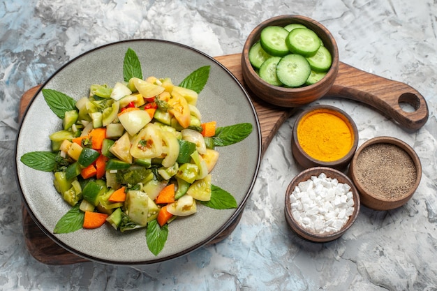 Free Photo bottom view green tomato salad on oval plate on cutting board different spices on dark background