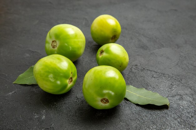 Bottom view green tomatoes and bay leaves on dark background