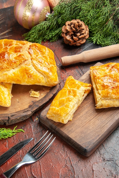 Bottom view penovani khachapuri on wood board rolling-pin pine tree branches and cones on dark red table