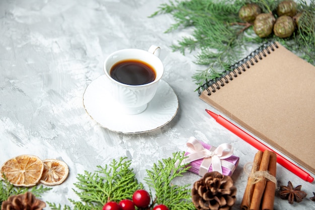 Bottom view pine tree branches cup of tea small gifts xmas tree toys notebook pencil on grey background