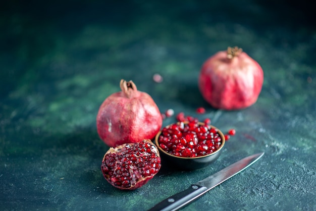 Free photo bottom view pomegranate seeds bowl pomegranates knife on table free space