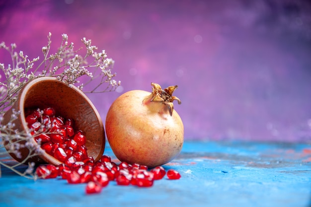 Bottom view pomegranate seeds in wooden bowl a pomegranate on purple free place