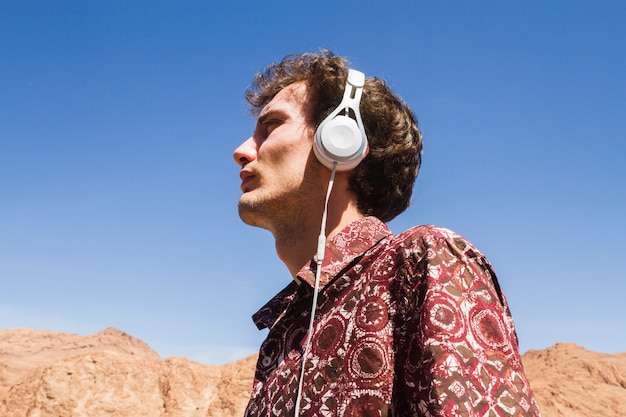 Free Photo bottom view portrait of man listening to music in desert