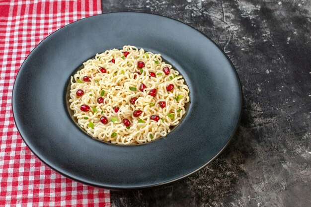 Bottom view ramen noodles on dark round plate red and white checkered tablecloth on dark table