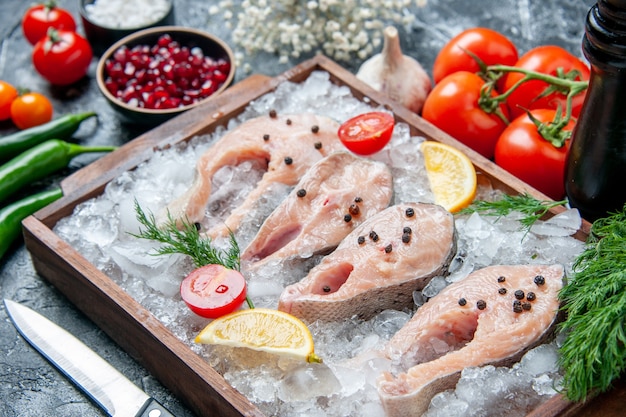 Bottom view raw fish slices with ice lemon slices on wood board bowls with pemagranate seeds sea salt on table