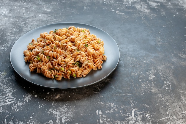 Bottom view rotini pasta on round plate on dark surface copy place