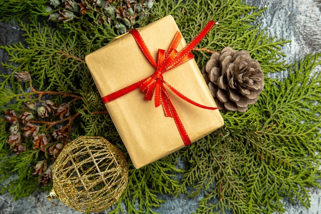 Free photo bottom view small gift tied with red ribbon on pine branches pinecones xmas ball