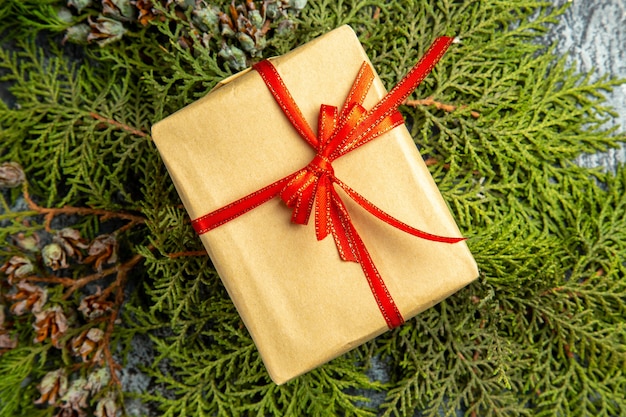 Free photo bottom view small gift tied with red ribbon on pine branches