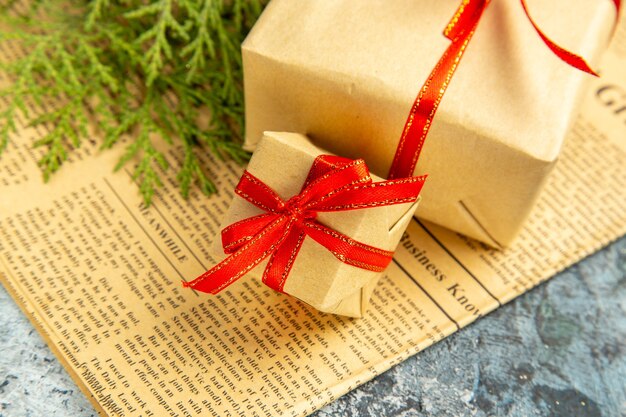 Bottom view small gifts tied with red ribbon on newspaper on dark background