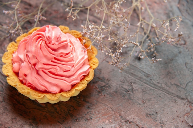 Free photo bottom view small tart with pink pastry cream on dark red table copy space