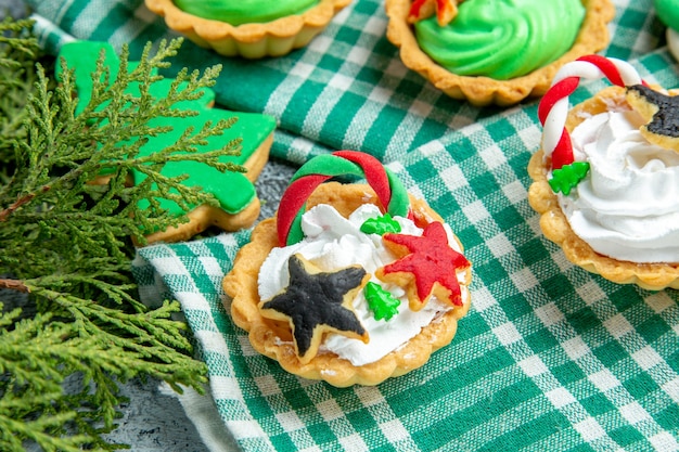 Free photo bottom view small xmas tarts on tablecloth pine branches on grey table