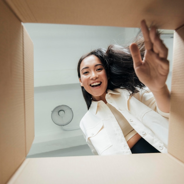 Bottom view smiley woman looking on a box