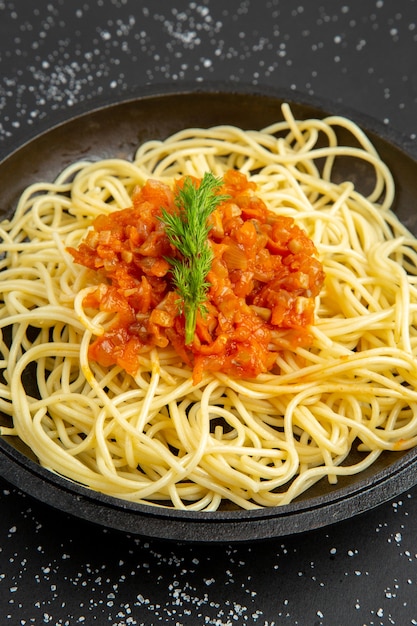 Bottom view spaghetti with sauce in frying pan on black table