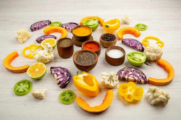 Bottom view spices bowls cut bell pepper cauliflower cut pumpkin cut red cabbage cut green tomatoes on table