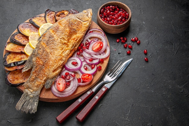 Free Photo bottom view tasty fish fry fried aubergines cut onions on wood board and other stuffs on dark background