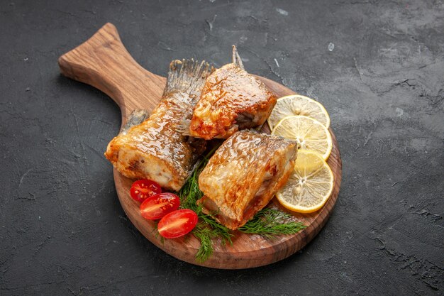 Bottom view tasty fish fry lemon slices cut cherry tomatoes on cutting board on black table