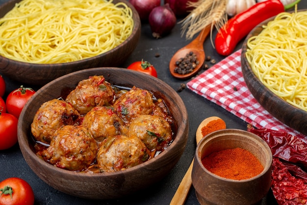 Free Photo bottom view tasty meatball soup in bowl spaghetti in bowl wooden spoons red tomatoes on table