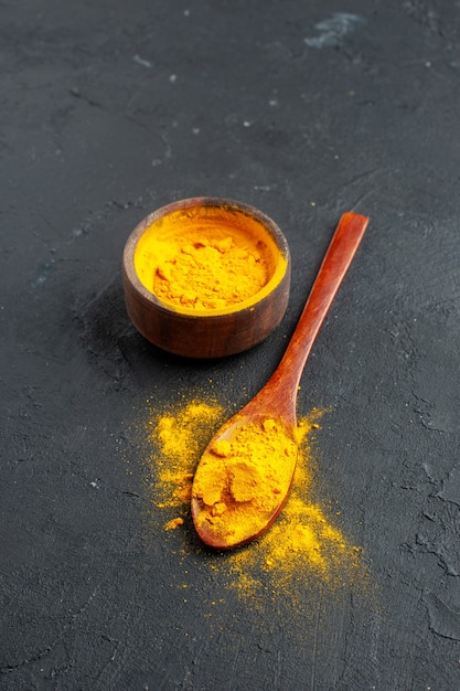 Free Photo bottom view turmeric bowl turmeric in wooden spoon on dark surface