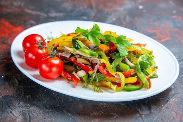 Bottom view vegetable salad cherry tomatoes on oval plate on dark red isolated surface