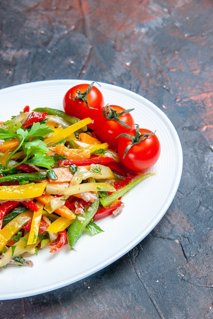 Bottom view vegetable salad on oval plate on dark surface