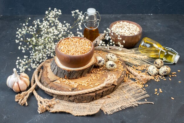 Bottom view wheat grains in bowl garlic on natural wood board quail eggs oil bottle oats bowl gypsophila flowers on table