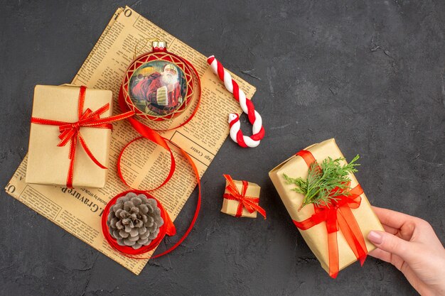 Bottom view xmas gifts in brown paper ribbon xmas tree toy on newspaper on dark background