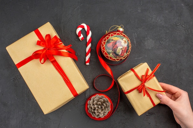 Bottom view xmas gifts in brown paper ribbon xmas tree toy on newspaper on dark background