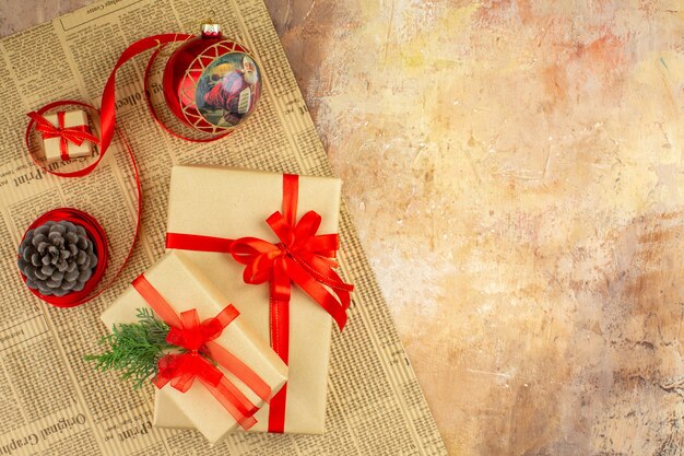 Bottom view xmas gifts in brown paper ribbon xmas tree toy on newspaper on dark background