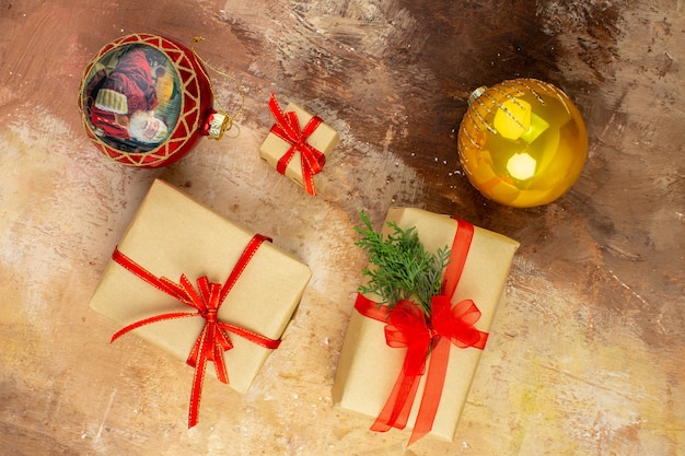 Free photo bottom view xmas gifts in brown paper ribbon xmas tree toy on newspaper on dark background