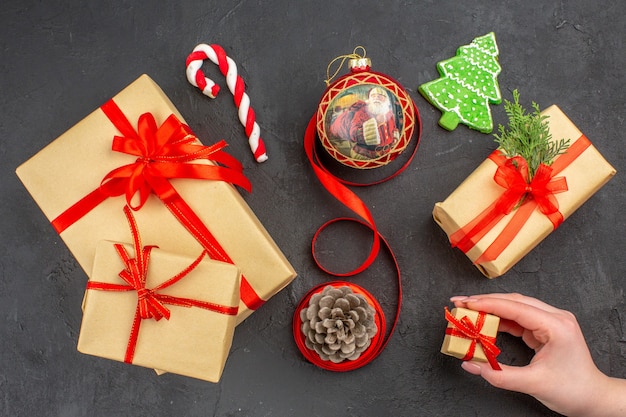 Bottom view xmas gifts in brown paper ribbon xmas tree toy on newspaper on dark