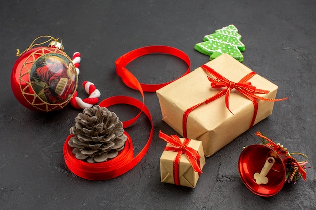 Bottom view xmas gifts in brown paper ribbon xmas tree toy on newspaper on dark