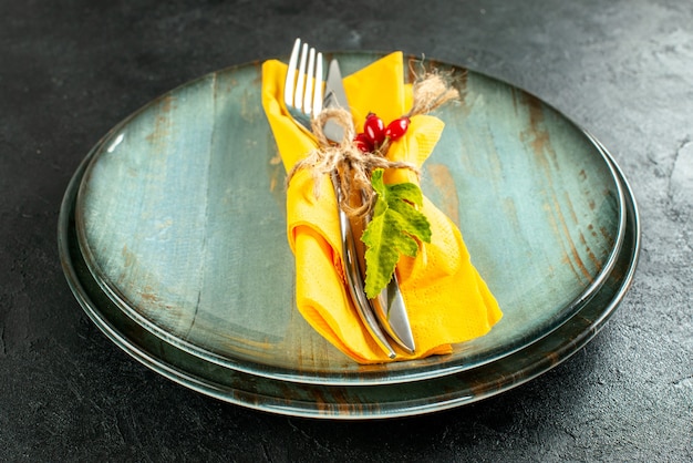 Free photo bottom view yellow napkin knife and fork tied with rope on plates on black table