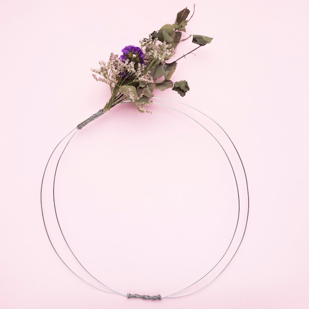 Free Photo bouquet of flower tied on metallic wire ring for frame on pink background