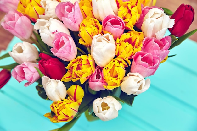 Bouquet of fresh multicolor tulip flowers on old blue wooden table