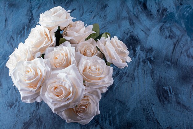 Bouquet of many white roses placed on blue.