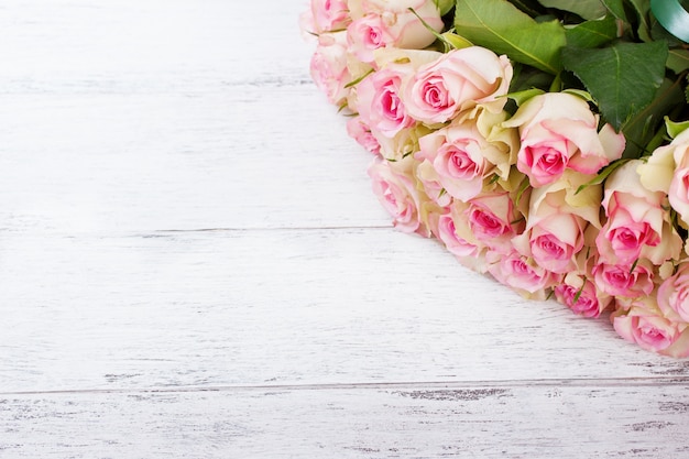 Bouquet of pink roses with blue ribbon on a vintage wooden background