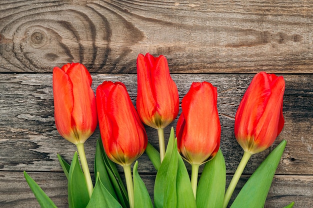 Free photo bouquet of red tulips on a wooden background top view