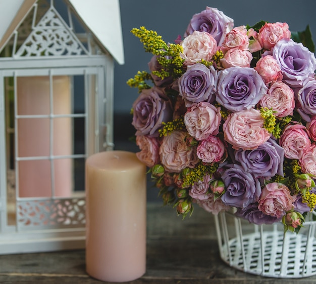 Free photo a bouquet of red and violet roses with leaves with pink candles around