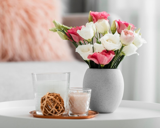 Free Photo bouquet of roses in a vase next to decorative objects