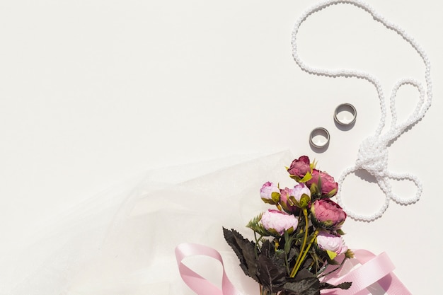 Free photo bouquet of roses next to wedding items with copy space