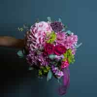 Free photo a bouquet of variety of flowers with rich colors and leaves in the hands of a bride on wall