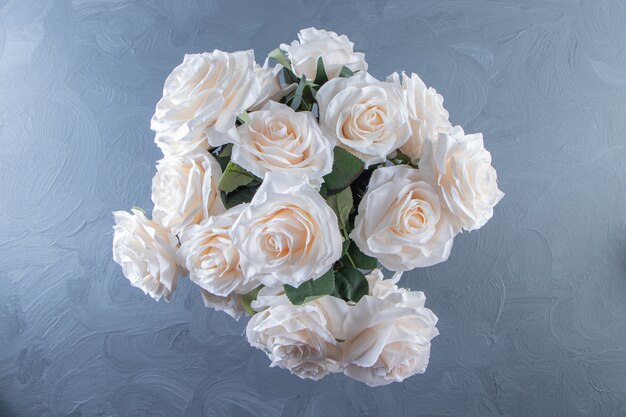 A bouquet of white flowers in a bucket, on the white table.