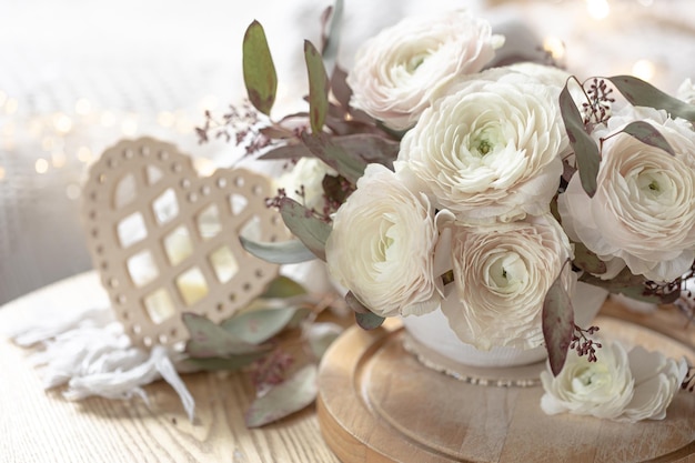 Bouquet of white ranunculus flowers on a blurred background with a heart