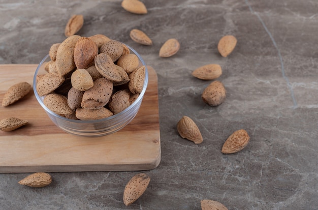 A bowl of almonds on a tray and scattered almonds on the marble surface