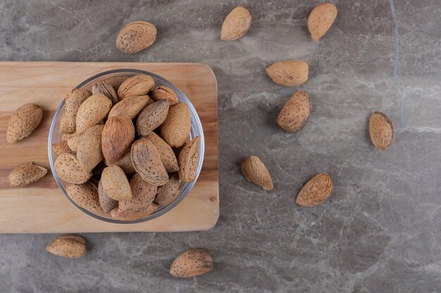 A bowl of almonds on a tray and scattered almonds on the marble surface