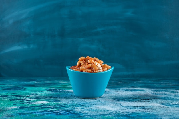 Bowl of baked beans, on the blue table. 